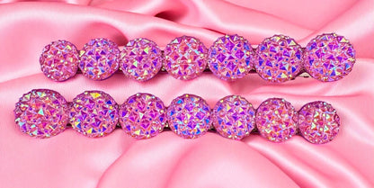 Set of pink and purple glittery hair ties on a pink satin background