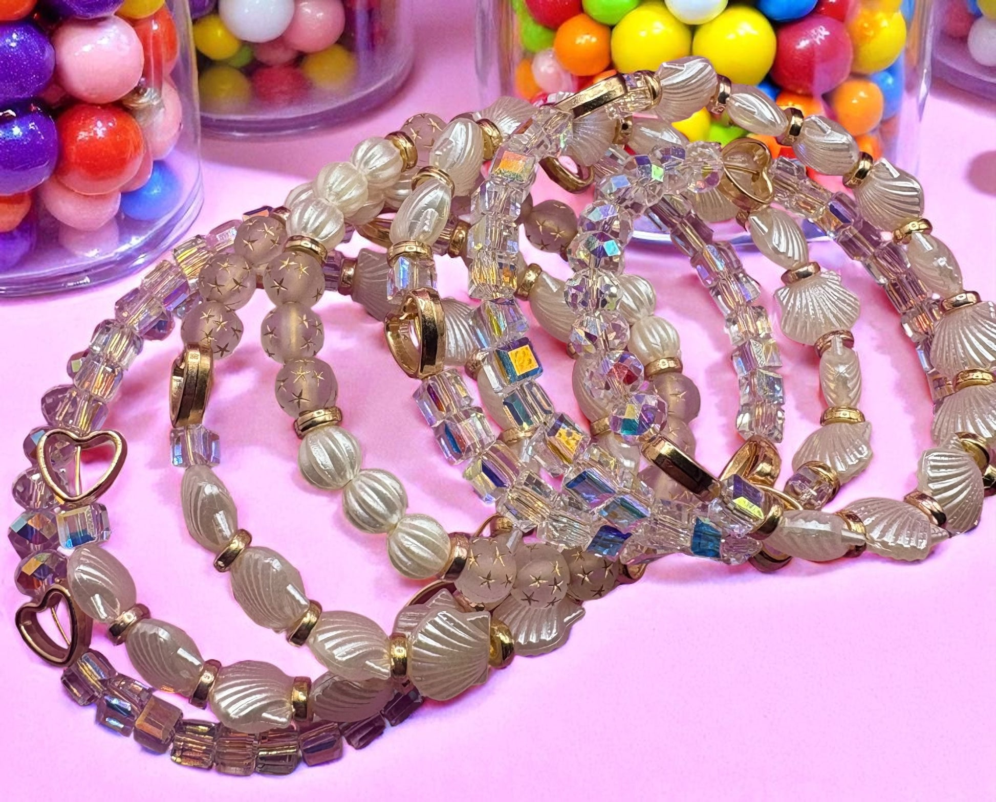 Decorative beaded necklace on a pink background with colorful gumballs in the background