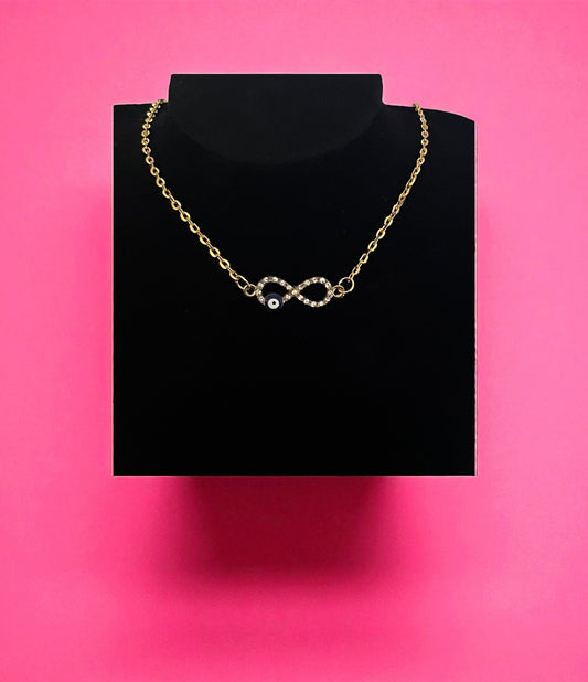 Gold chain necklace with a heart pendant on a black stand against a pink background