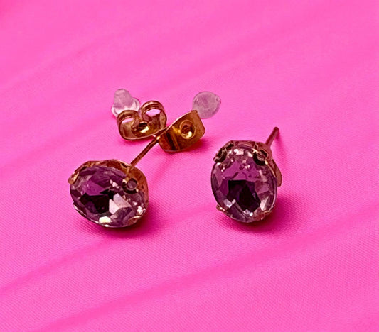 Pair of pink gemstone earrings on a pink background