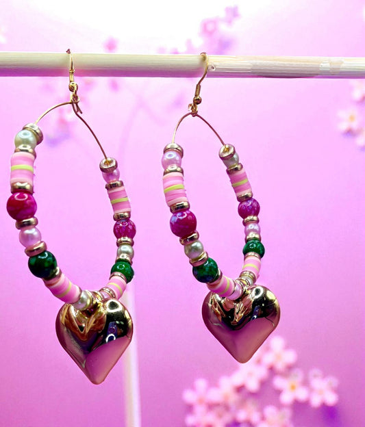 Heart-shaped beaded earrings on a pink background with floral elements.