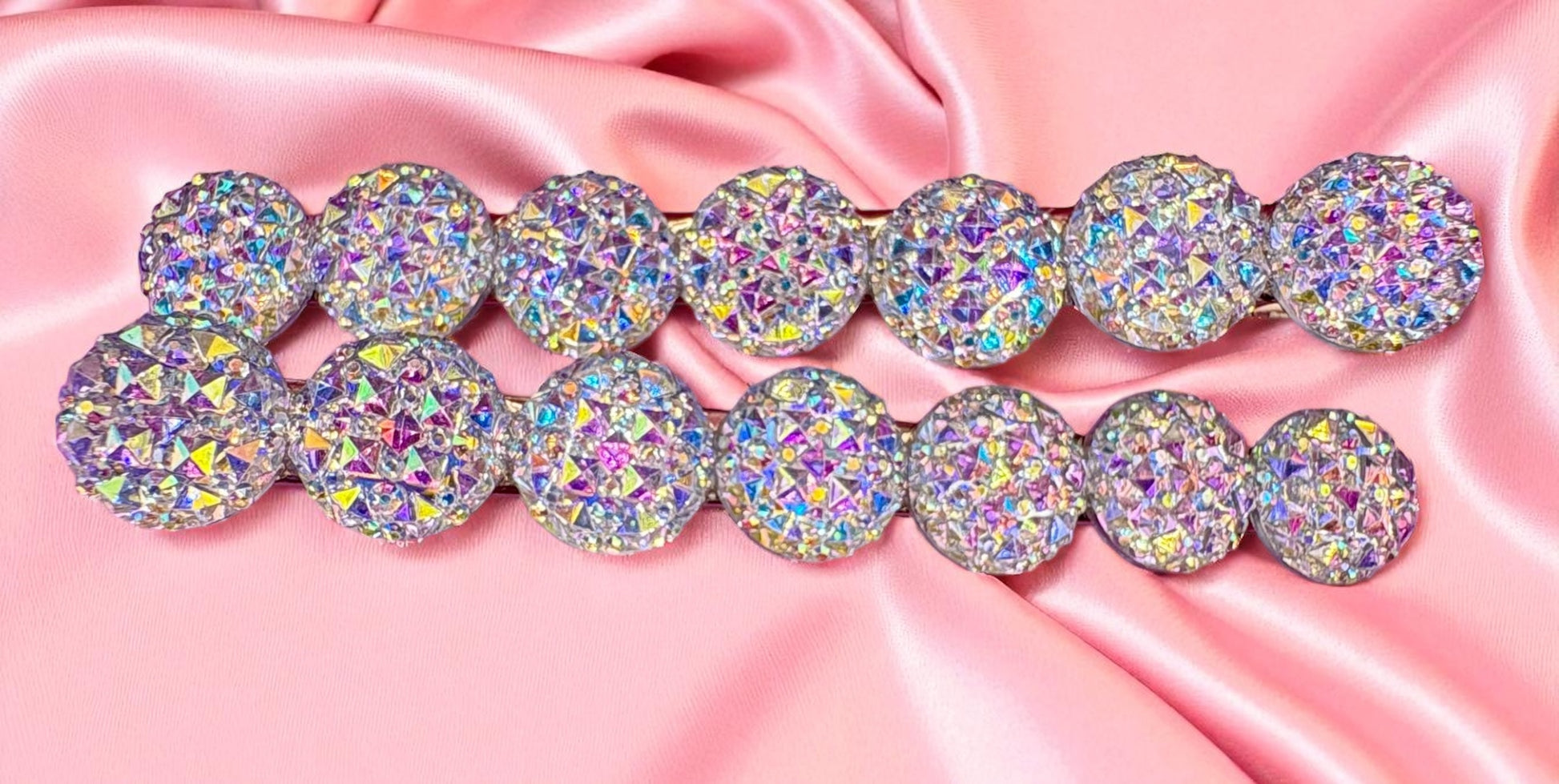 Multicolored glittery round stones on a pink satin background