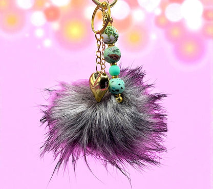 Keychain with fur ball and beads on a pink background