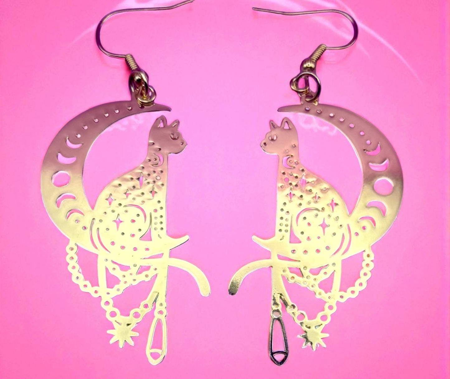 Luminous cat-shaped earrings on a pink background