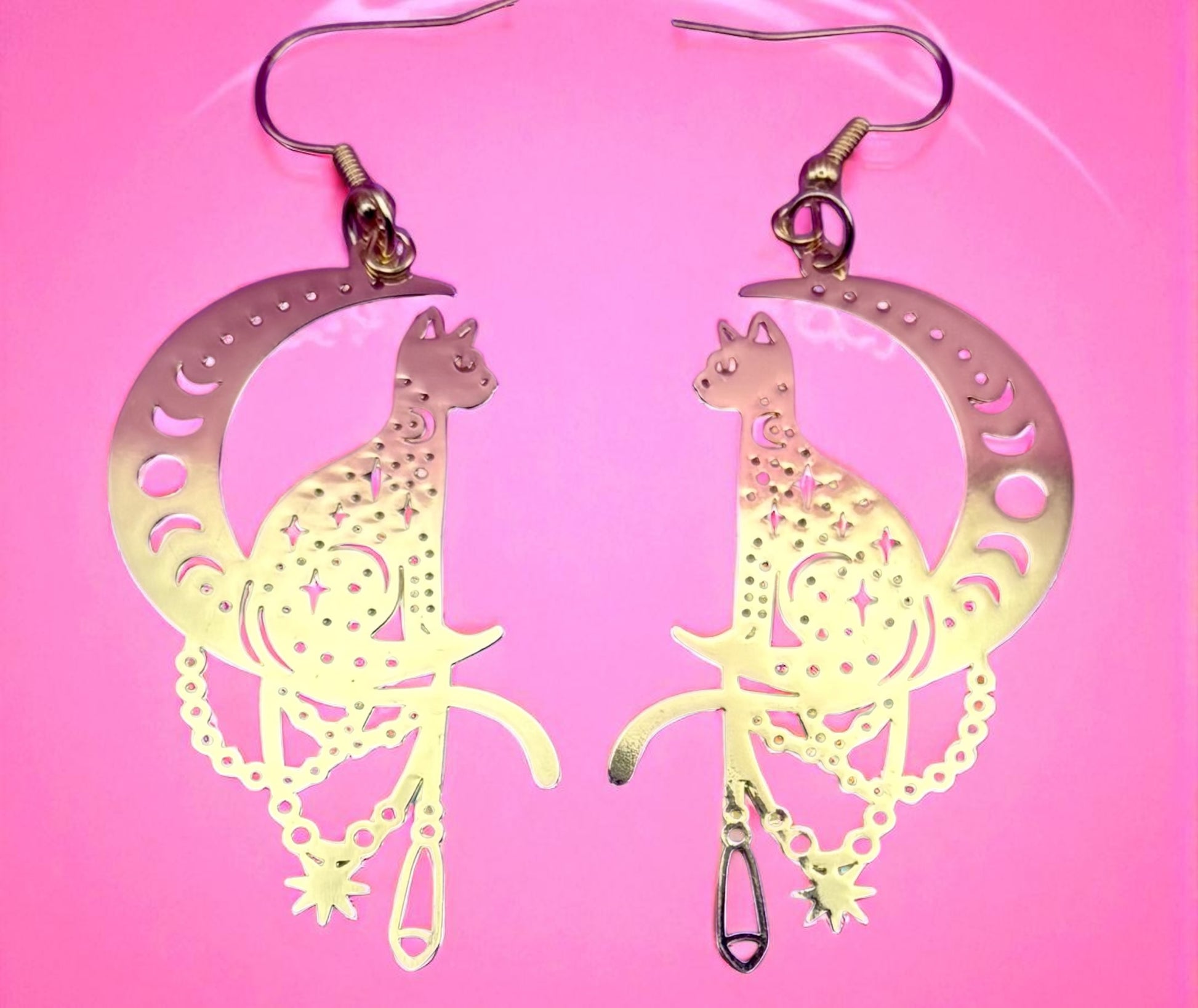 Luminous cat-shaped earrings on a pink background
