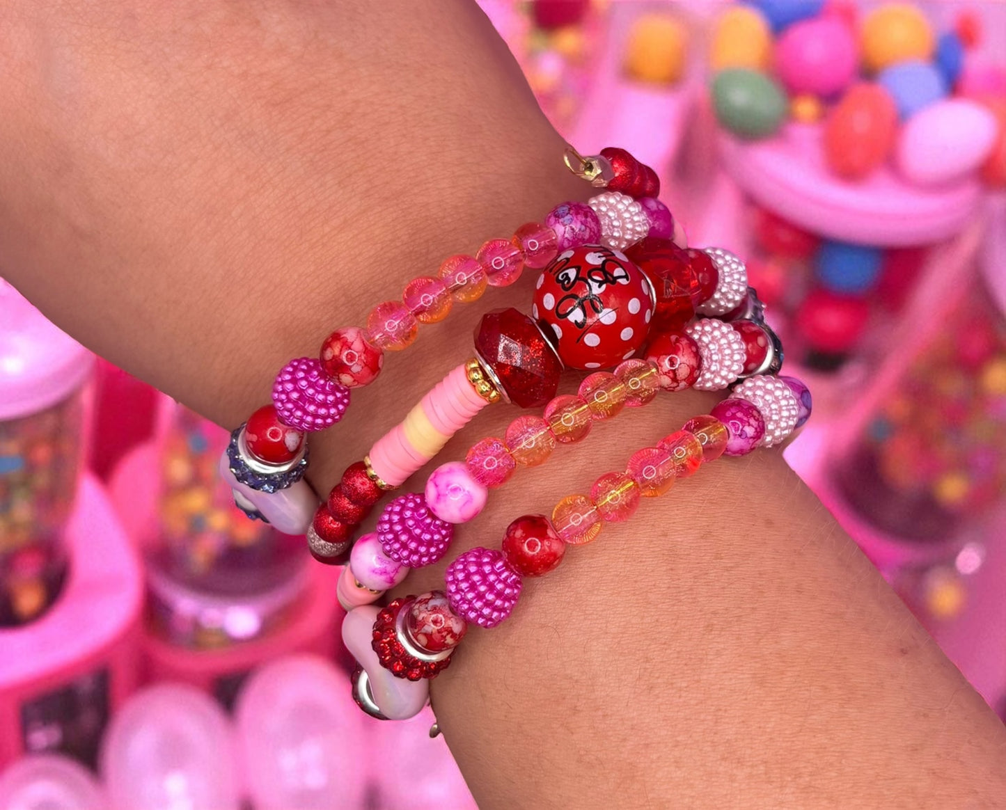 Colorful beaded bracelets on a wrist with a candy-themed background