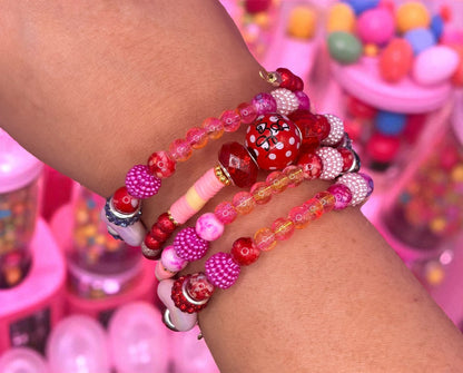 Colorful beaded bracelets on a wrist with a candy-themed background