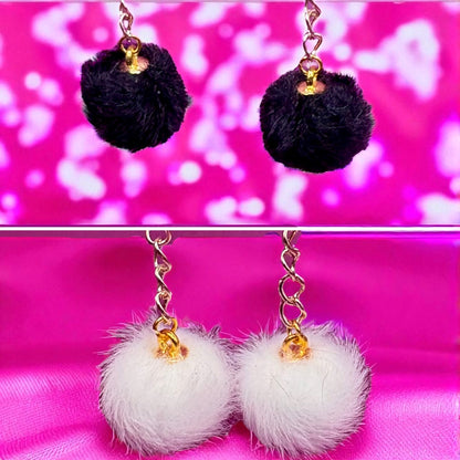 Black and white pom-pom earrings on a pink background