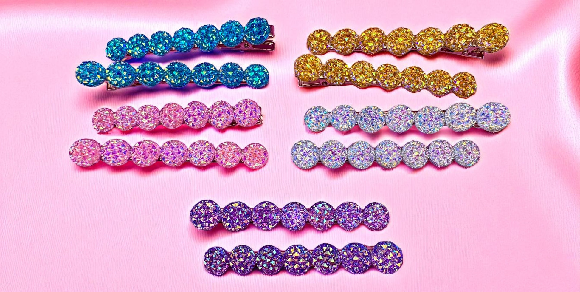 Set of colorful rhinestone hair clips on a pink background