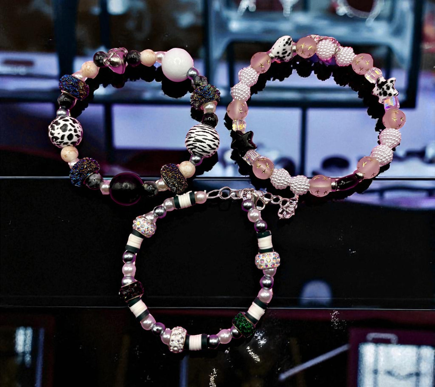 Two beaded bracelets on a dark surface with a blurred background