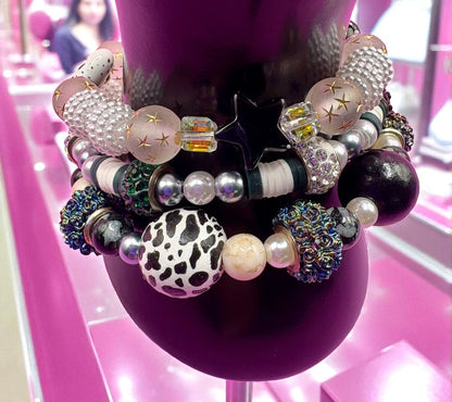 Colorful beaded bracelets on a mannequin head with a pink background