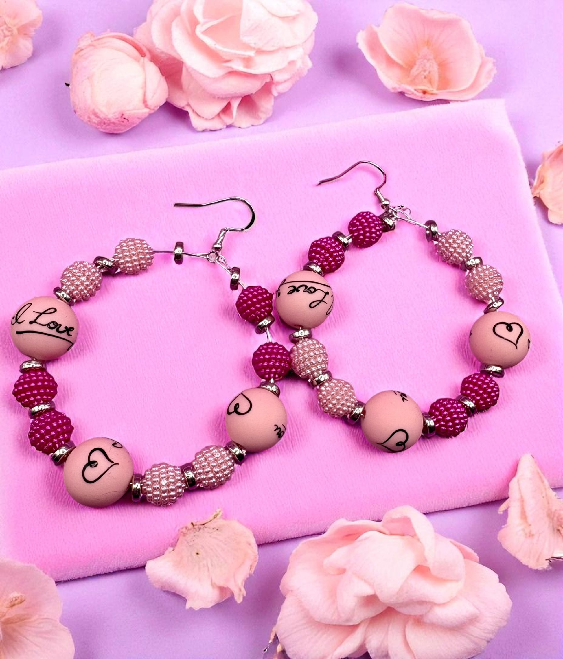 Pair of beaded earrings on a pink surface with flowers around