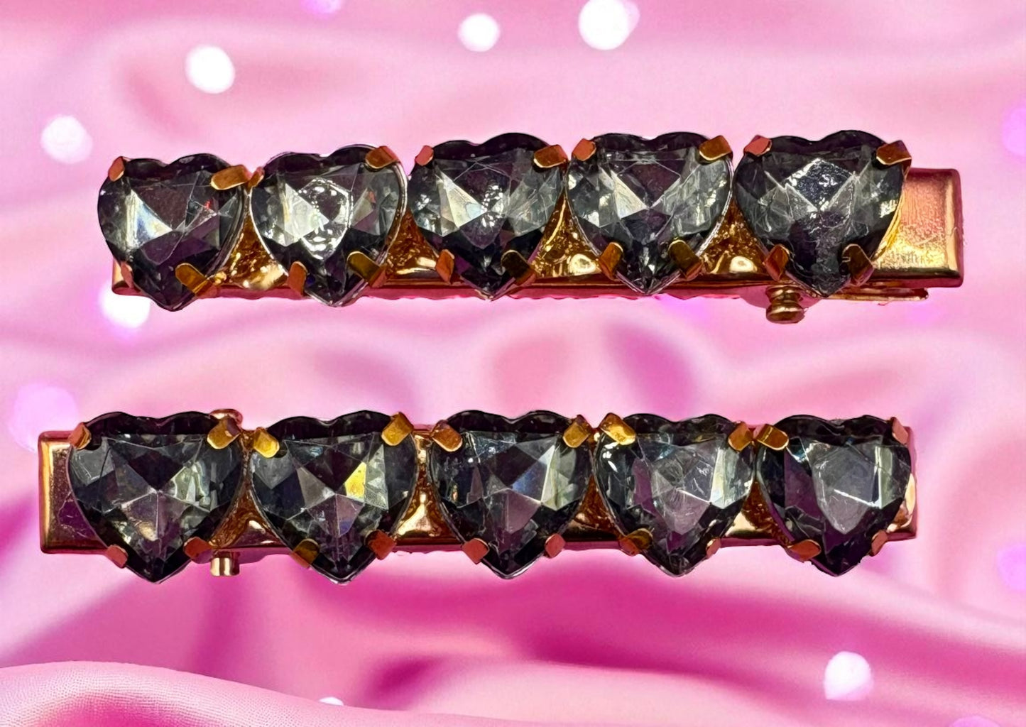 Two heart-shaped gemstone hair clips on a pink background