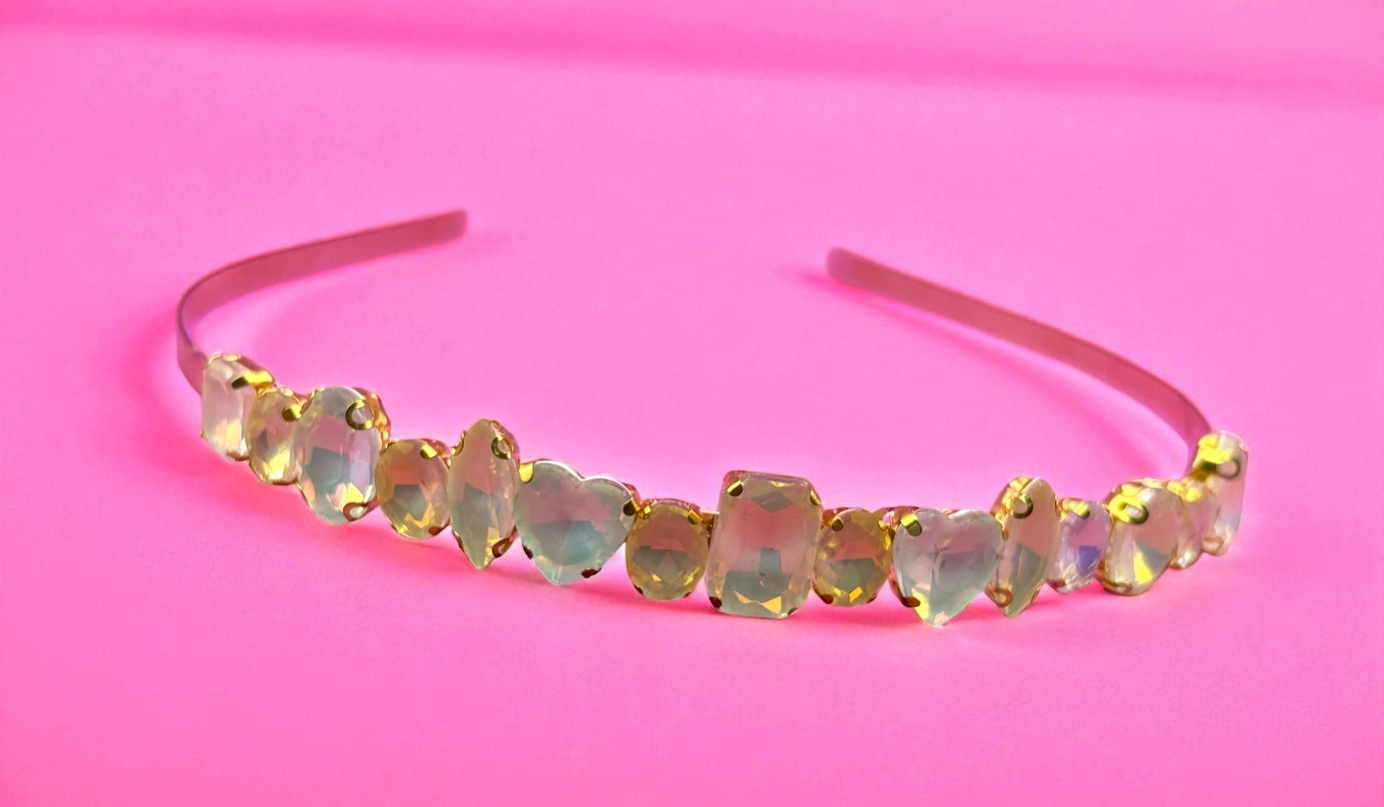 Opal heart-shaped gemstone headband on a pink background
