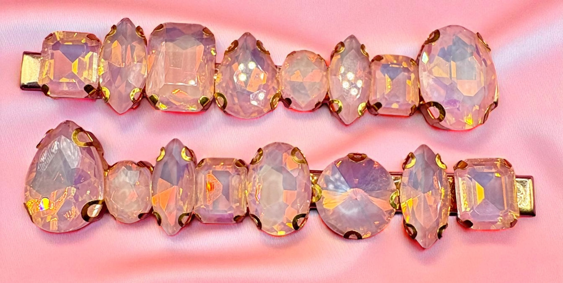 Pair of ornate hair clips with pink and gold gemstones on a pink background