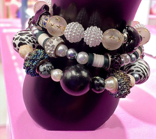 Stack of colorful beaded bracelets on a purple stand with a pink background