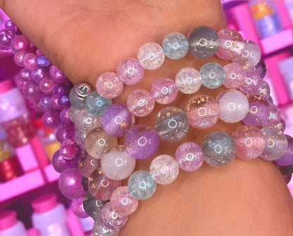 Multicolored beaded bracelets on a person's wrist with a blurred background