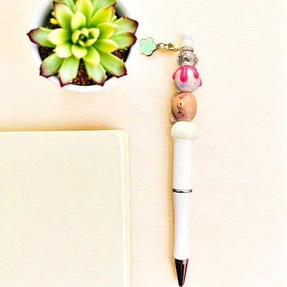 Decorative pen with a small figurine and beads on a light background
