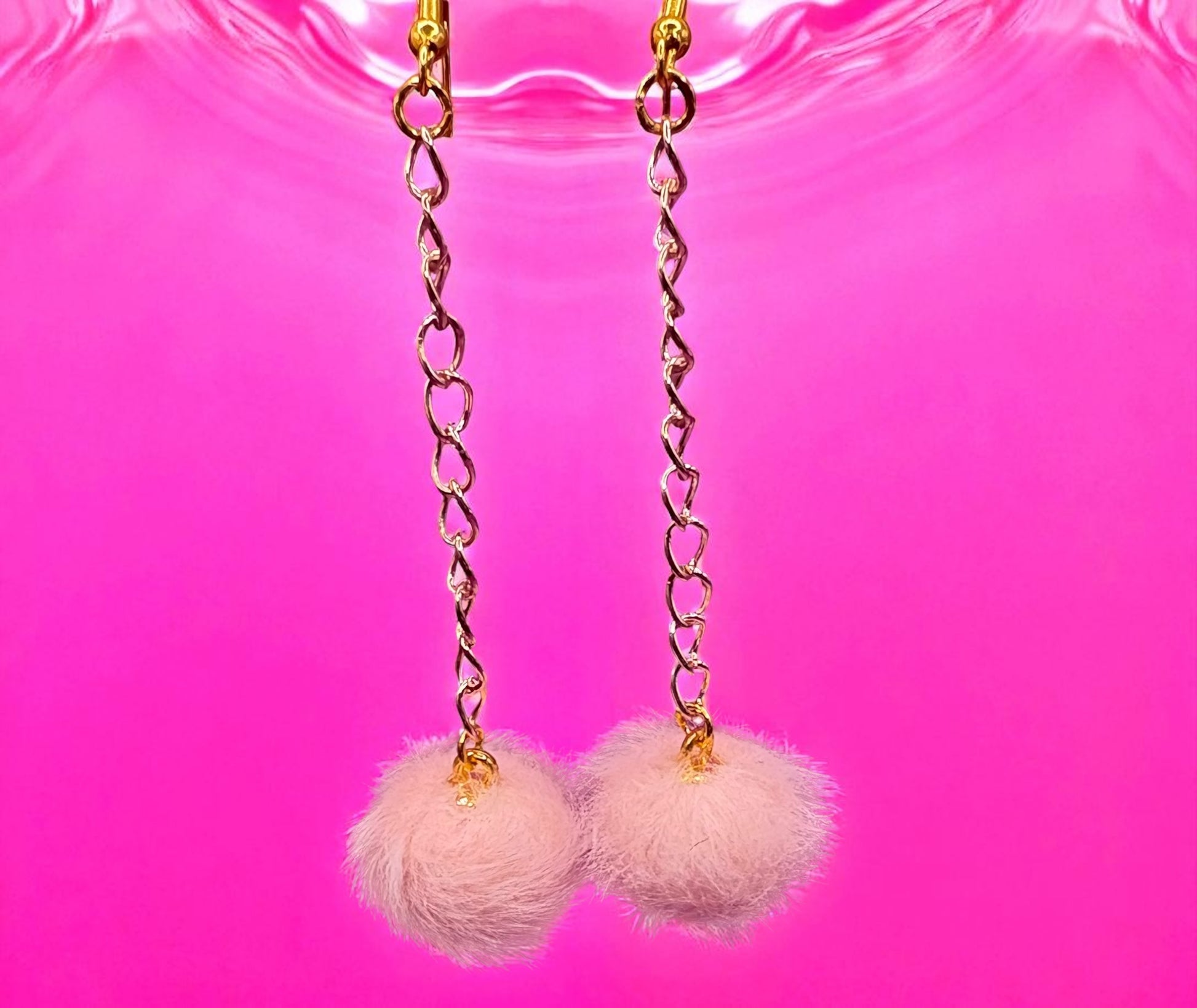 Earrings with pink fluffy balls on a pink background
