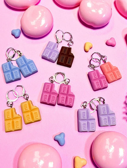 Colorful chocolate bar  earrings on a pink background with heart shapes.