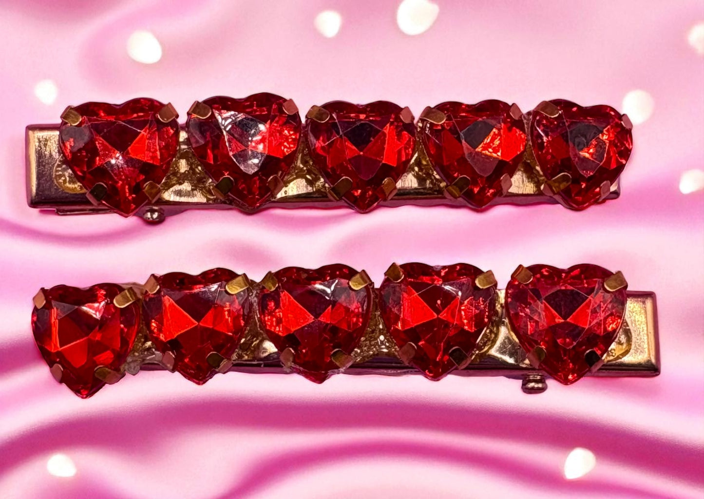 Two red heart-shaped jhair clips  pieces on a pink background