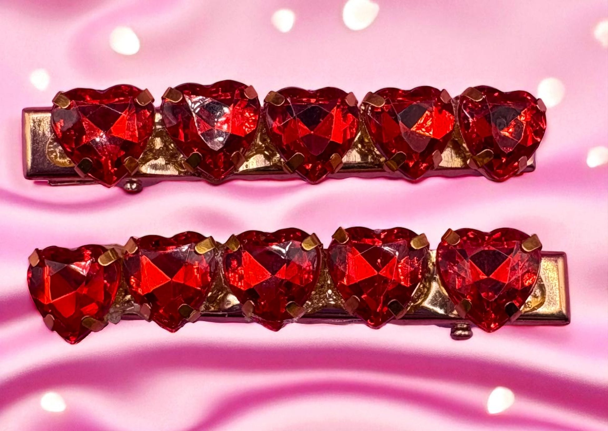 Two red heart-shaped jhair clips  pieces on a pink background