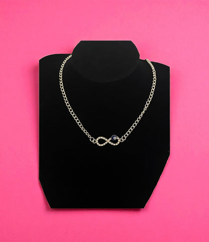 Necklace on a black stand against a pink background