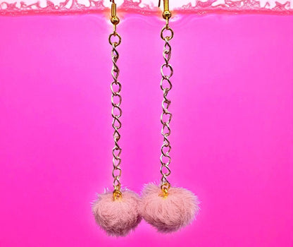 Pink pom-pom earrings with gold chains on a pink background