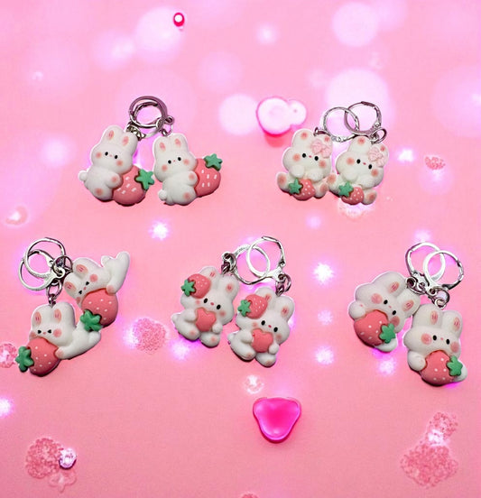 Set of cute keychains with bear and strawberry designs on a pink background