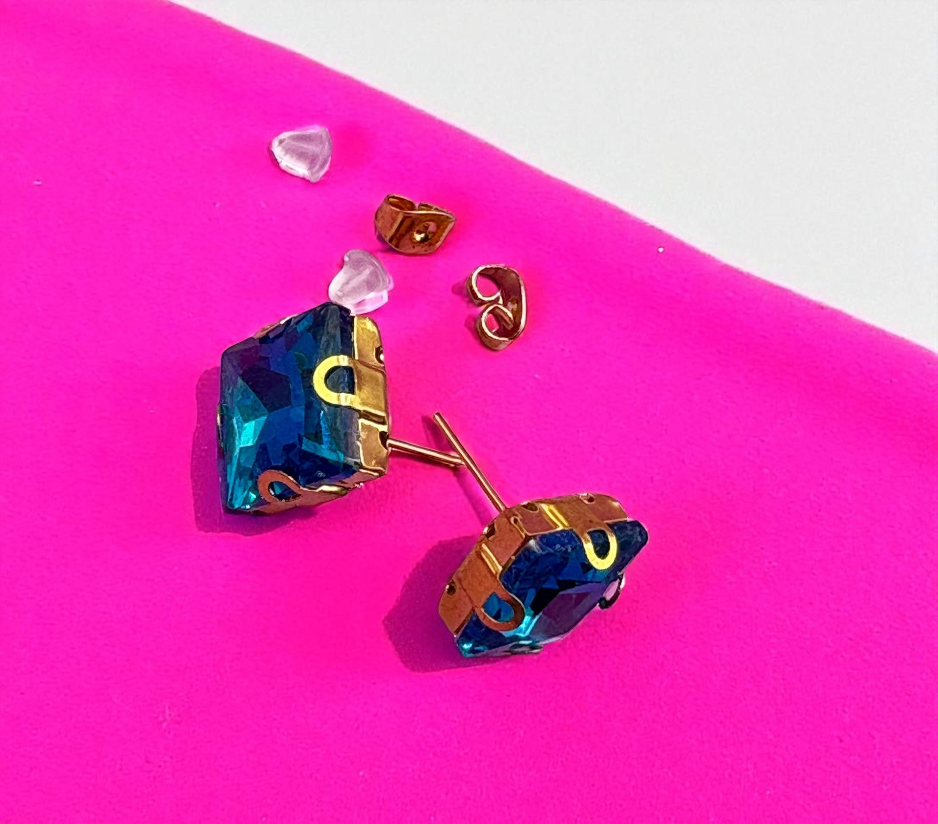 Colorful geometric earrings on a pink and white background