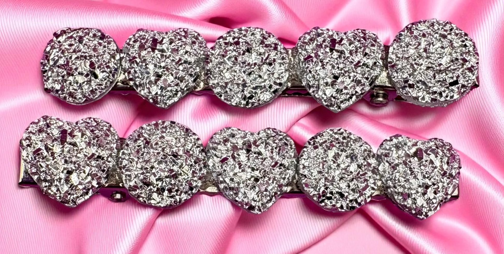 Silver heart-shaped hair clips  on a pink satin background