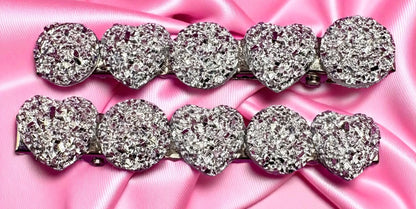 Silver heart-shaped hair clips  on a pink satin background