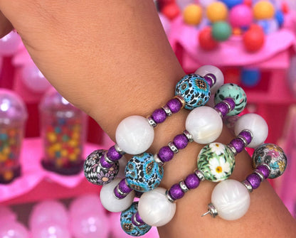 Colorful beaded bracelets on a wrist with a blurred gumball machine in the background
