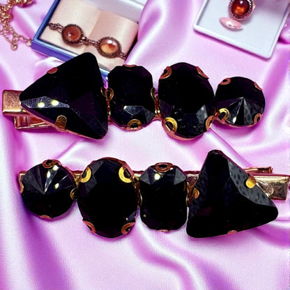 Black hair clips with gold accents on a pink satin background