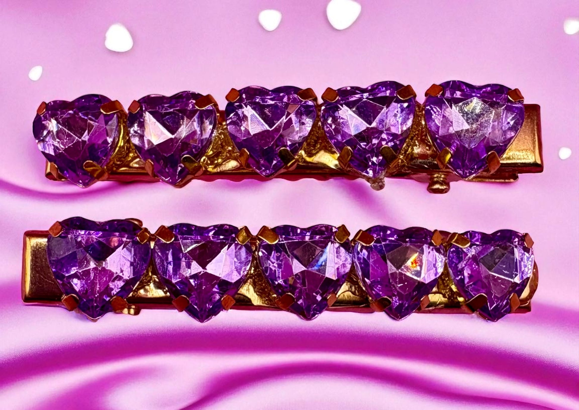 Purple heart-shaped gemstone hair clips on a pink background