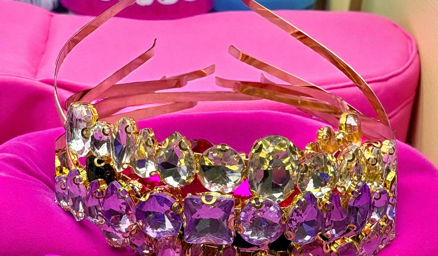 Colorful tiara with crystals on a pink surface