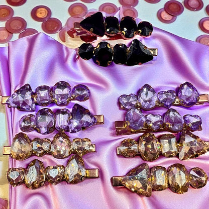 Set of crystal hair clips on a satin surface with scattered crystals in the background