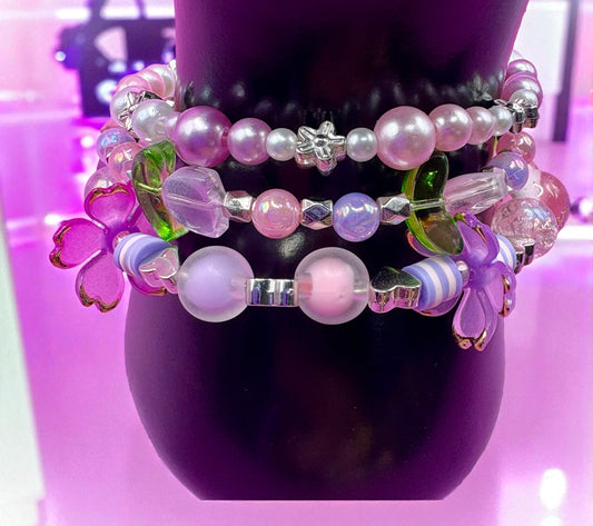 Stack of colorful beaded bracelets on a purple mannequin bust.