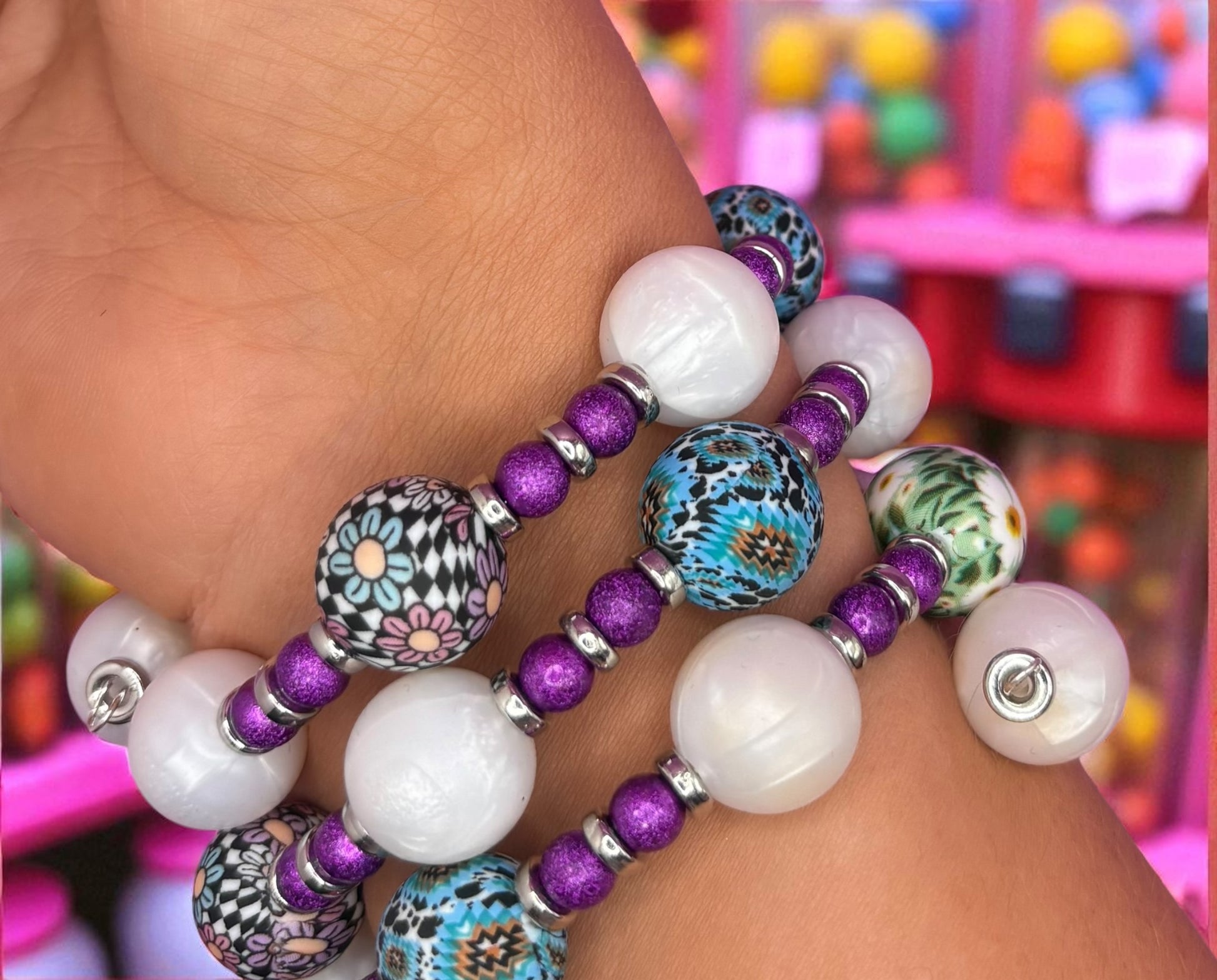 Colorful beaded bracelets on a wrist with a blurred colorful background