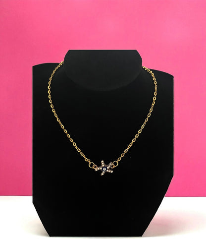 Gold necklace on a black bust against a pink background