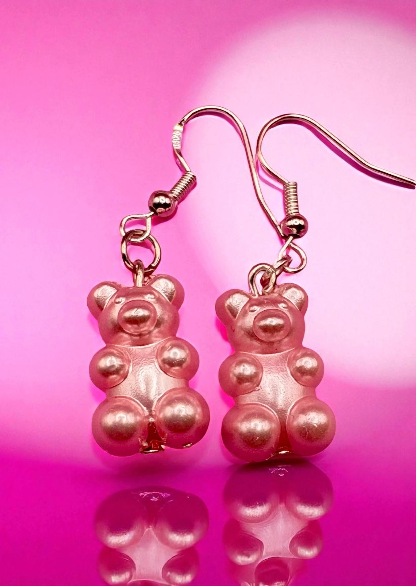 Pink gummy bear-shaped earrings on a pink background