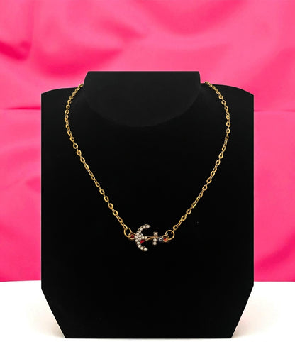 Gold necklace on a black stand with a pink background