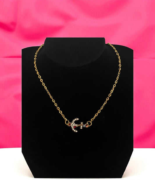 Gold necklace on a black stand with a pink background
