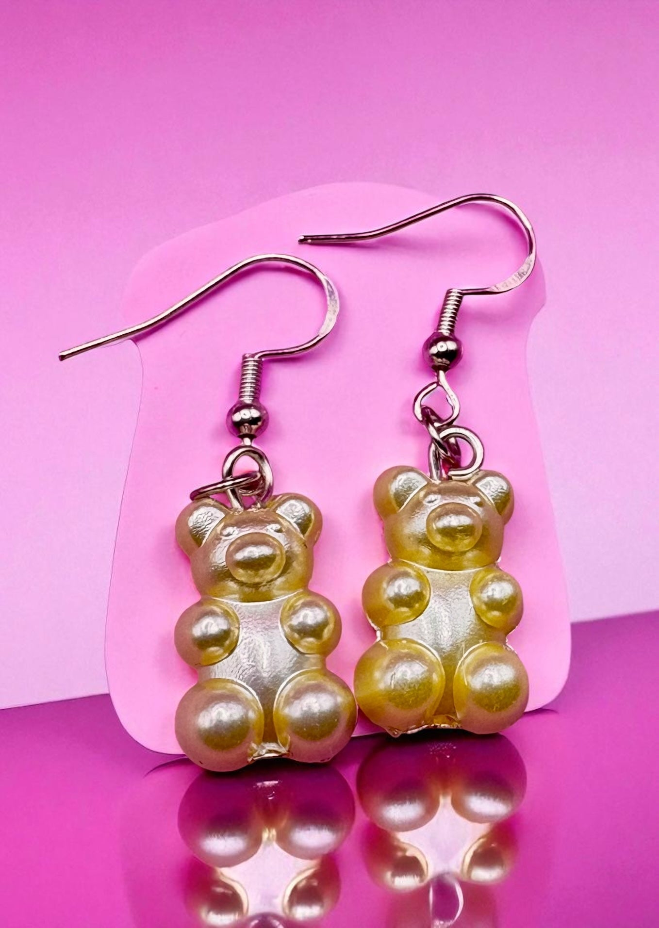 Gummy bear-shaped earrings on a pink background