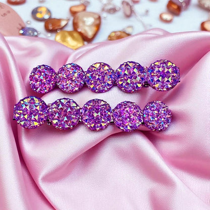 Purple gemstone hair clips on pink satin fabric