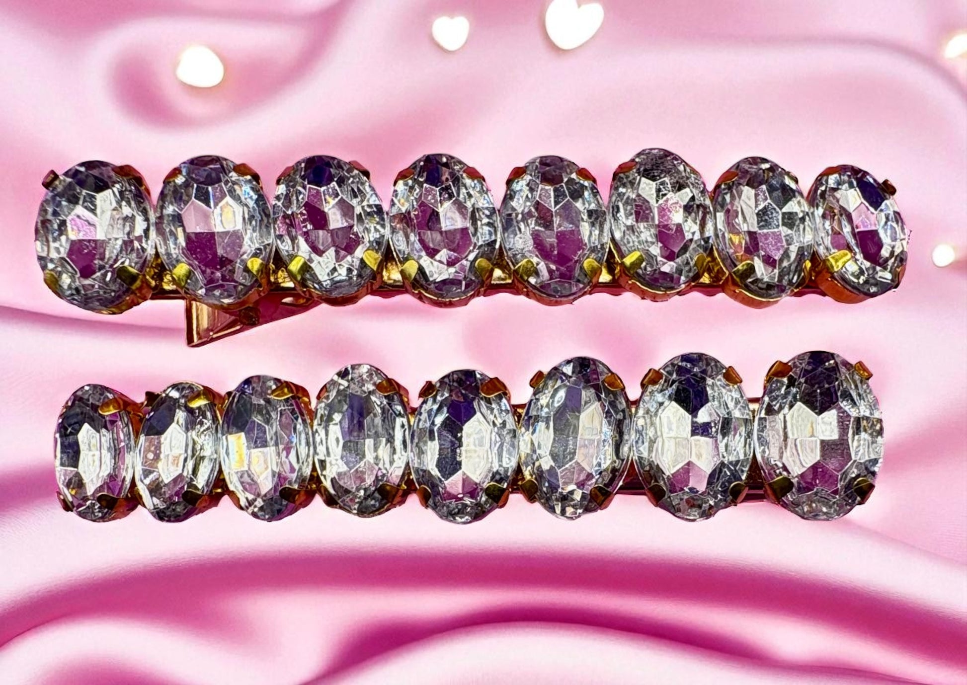 Pair of diamond-studded hair clips on a pink background