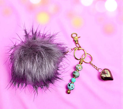 Keychain with fur pom-pom and heart-shaped charm on a pink background