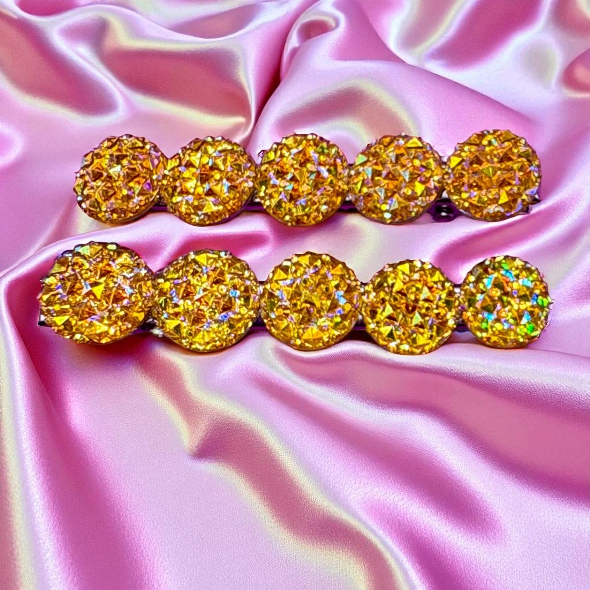 Pair of gold hair clips  on a pink satin background