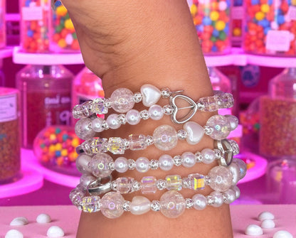 Stack of pearl and crystal bracelets on a wrist with a colorful candy store background