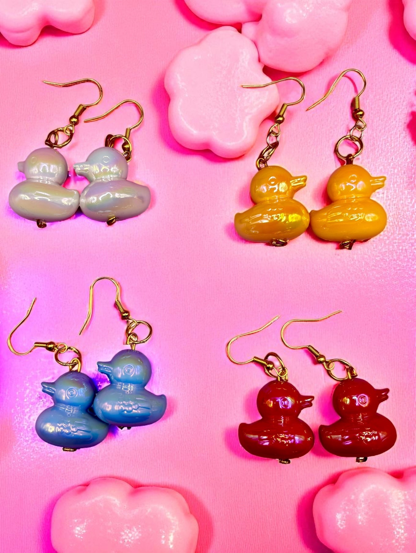 Four pairs of colorful duck-shaped earrings on a pink background